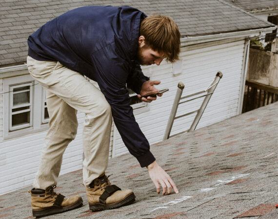 man walking on houses roof while performing inspections