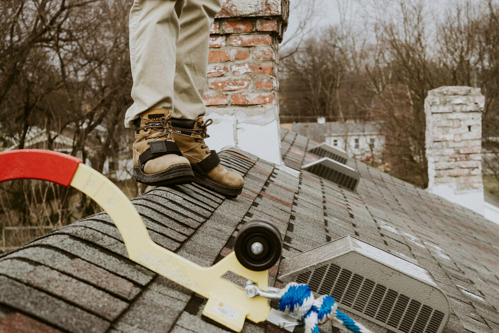 A Knight's Solutions technician on a roof, their Cougar Paws and Ridge Pro are shown on a roof top. 