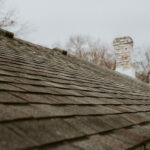 A shingle roof with an inspectors boots show as they perform an inspection.