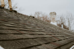 A shingle roof with an inspectors boots show as they perform an inspection.