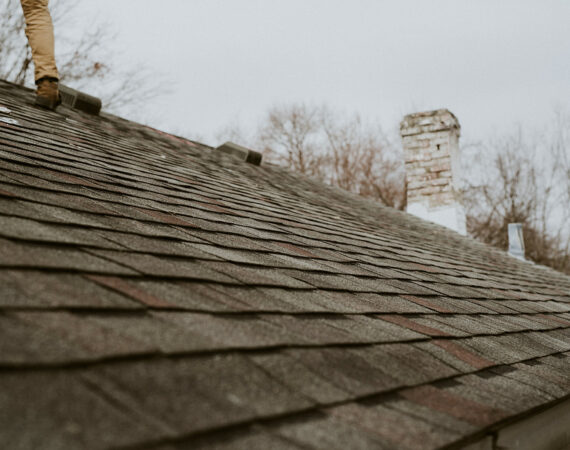 A shingle roof with an inspectors boots show as they perform an inspection.